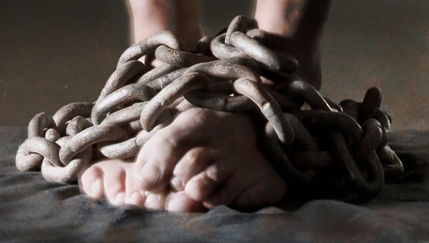 Close-up of bare feet bound in heavy metal chains