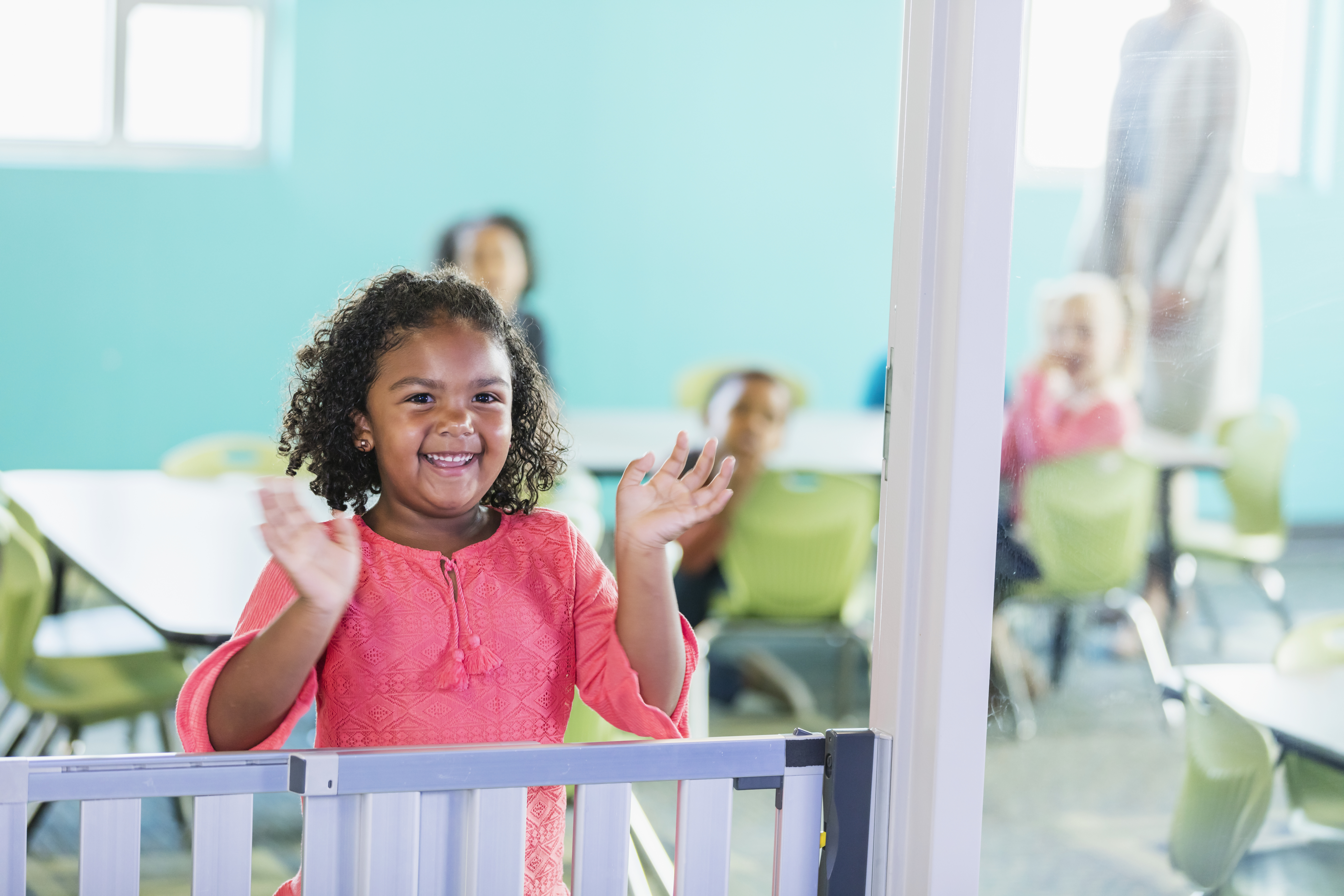 Mixed race girl in preschool smiling, waving