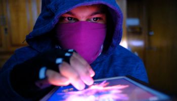 young hacker with digital tablet stealing information- data security theft idea