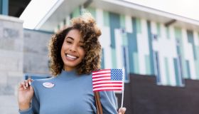 Woman smiles for camera and shows off "I voted" sticker