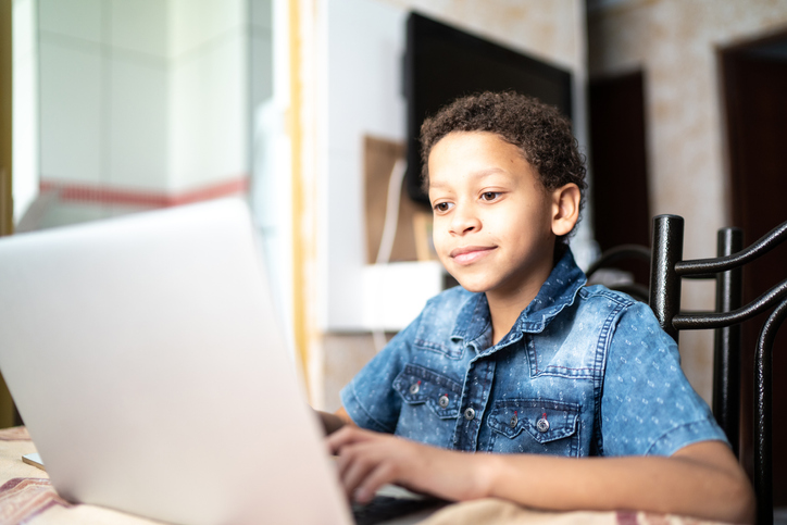 Child boy studying using laptop at home