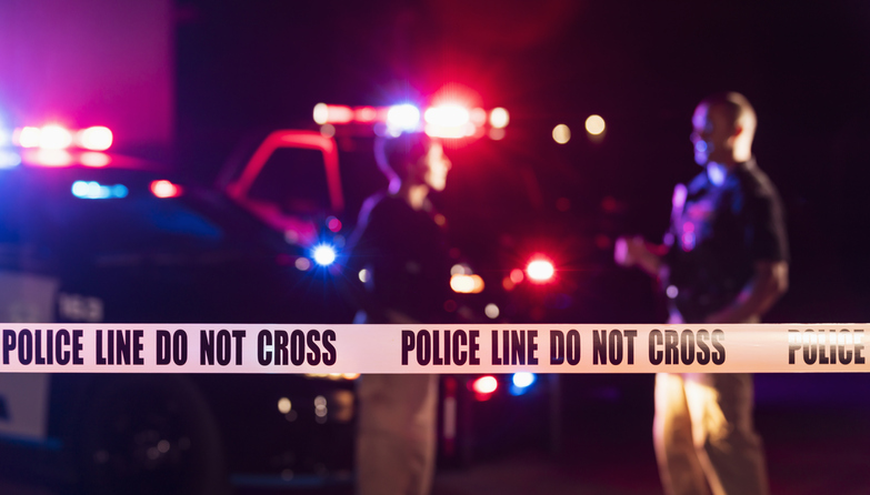 Two police officers standing in front of patrol cars