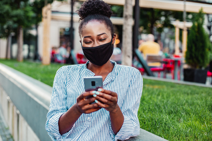 African American woman with mask using phone