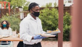 Waiter wears mask and gloves to serve at patio restaurant