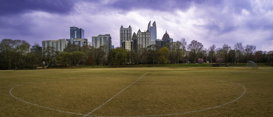 Atlanta City skyline in stormy winter with skyscrapers, buildings, and dramatic blue purple clouds over the soccer field of Piedmont Park in the Capital of the U.S. State of Georgia