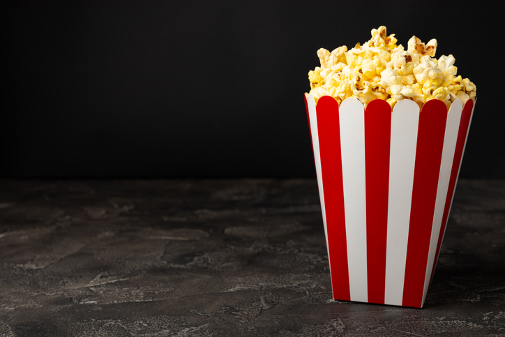 Tasty popcorn in buckets and cold cola drinks with cinema tickets, movie clapper and 3D eyeglasses on a bright colored background. Cinema concept. Watching a movie.Place for text. Copy space