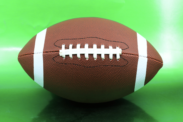 Leather american football on green background