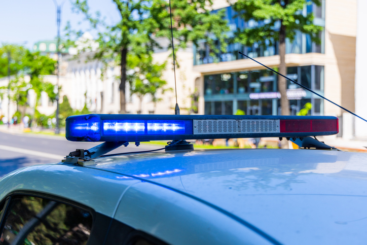 Close-up of a police cars flashing blue light bar on a city street, indicating an emergency or official presence
