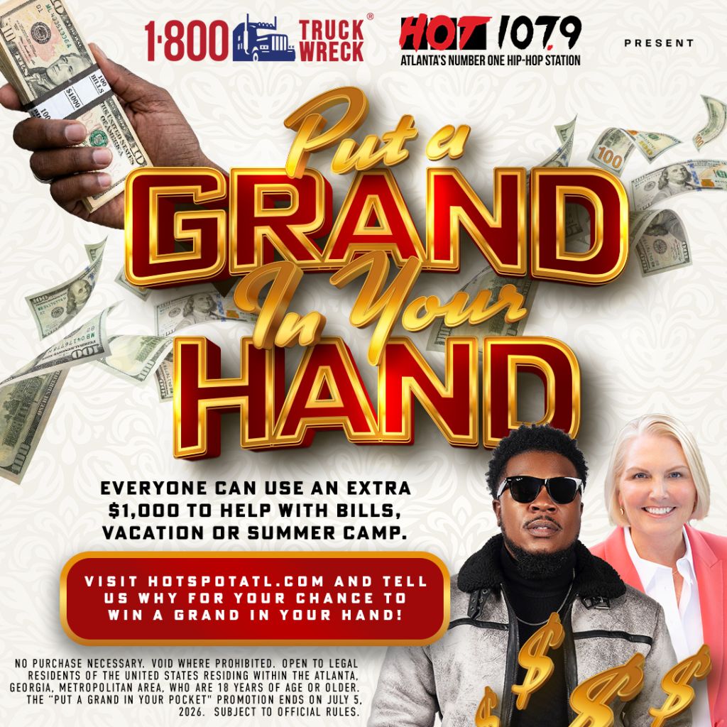 A hand holding cash, surrounded by more cash, with text promoting a "Put a Grand in Your Hand" contest from radio station HOT 107.9.