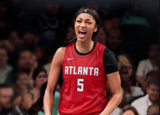 A woman in a red Atlanta jersey shouting with an intense expression on her face.